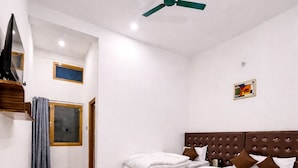 A bedroom with a bed, a ceiling fan, a window, and a door.