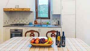 Une cuisine avec une fenêtre, un panier de fruits et des bouteilles de vin sur le comptoir.