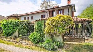 Une maison avec un jardin, une clôture en métal et un ciel dégagé.