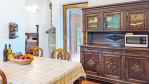 Un coin repas avec une table dressée pour deux personnes, un meuble en bois contenant un four à micro-ondes et un mur en pierre.