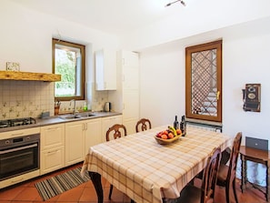 A kitchen with white cabinets, a stove, and a dining table with a checkered tablecloth.