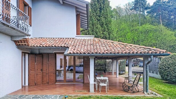 Une maison avec un toit en tuiles, un patio couvert et un jardin.