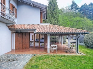 A house with a tiled roof, a covered patio, and a garden.