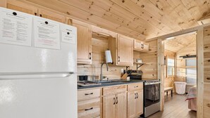 A wooden cabin kitchen with a refrigerator, sink, stove, and cabinets. - Cozy stay at Baling Out Farms (Southside)