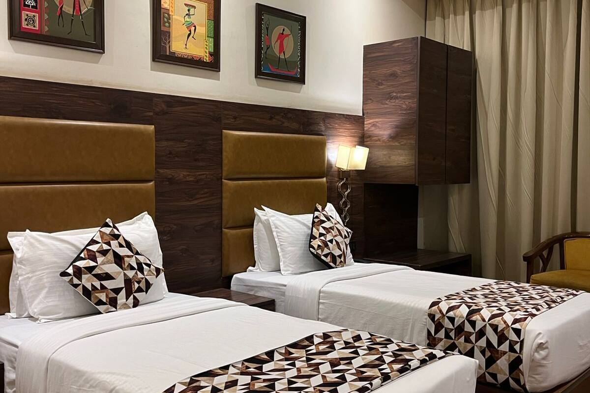 Habitación de hotel con dos camas, cabecero de madera, ventilador de techo y una obra de arte en la pared.