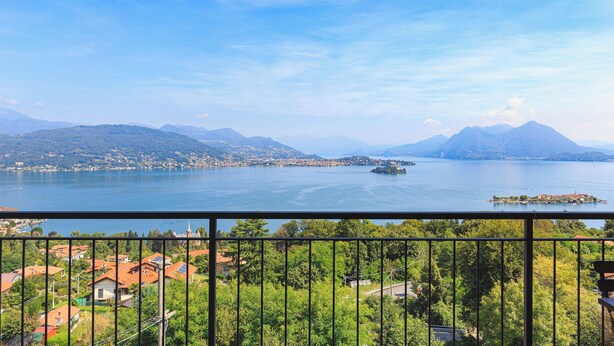Un lac avec des montagnes en arrière-plan, un balcon offrant une vue sur le lac et les environs.