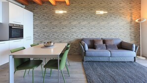 Une cuisine moderne avec des meubles blancs, un four encastré et un coin repas comprenant une table et des chaises.