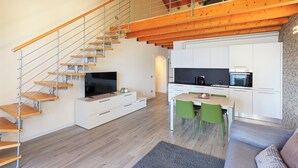 Un appartement moderne doté d’un escalier en bois, d’une cuisine, d’un coin repas et d’un salon.