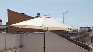 A rooftop terrace with lounge chairs, a large umbrella, and a view of the cityscape. - Spectacular penthouse with private terrace well communicated in the center of Granada (Granad)