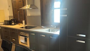 A modern kitchen with dark cabinetry, a stainless steel range hood, a built-in dishwasher, and a double sink. - Spectacular penthouse with private terrace well communicated in the center of Granada (Granad)