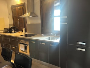 A modern kitchen with dark cabinetry, a stainless steel range hood, a built-in dishwasher, and a double sink. - Spectacular penthouse with private terrace well communicated in the center of Granada (Granad)