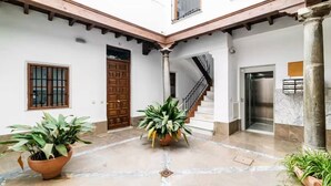 A courtyard with a wooden door, a staircase, and potted plants. - Spectacular penthouse with private terrace well communicated in the center of Granada (Granad)