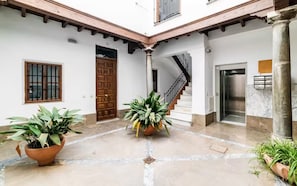 A courtyard with a wooden door, a staircase, and potted plants. - Spectacular penthouse with private terrace well communicated in the center of Granada (Granad)