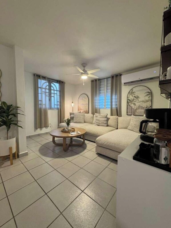 A living room with a sofa, coffee table, and a ceiling fan.