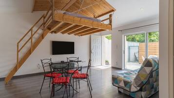 A modern interior with a dining area, a sofa, and a staircase.