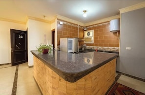 A kitchen with a granite countertop, a refrigerator, and a built-in oven. - Romantic Golf View Retreat – Cozy Elegance in Dreamland Compound (Giza Governorate)