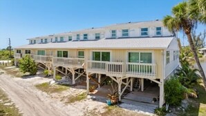 A beachfront hotel with multiple balconies, a sandy driveway, and palm trees. - Welcome to your slice of paradise on Little Gasparilla Island (Placida, Little Gasparilla Island)