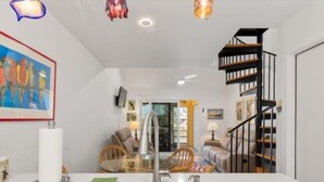 A modern kitchen with a stainless steel sink, a dining area with a glass table, and a staircase leading to a loft. - Welcome to your slice of paradise on Little Gasparilla Island (Placida, Little Gasparilla Island)