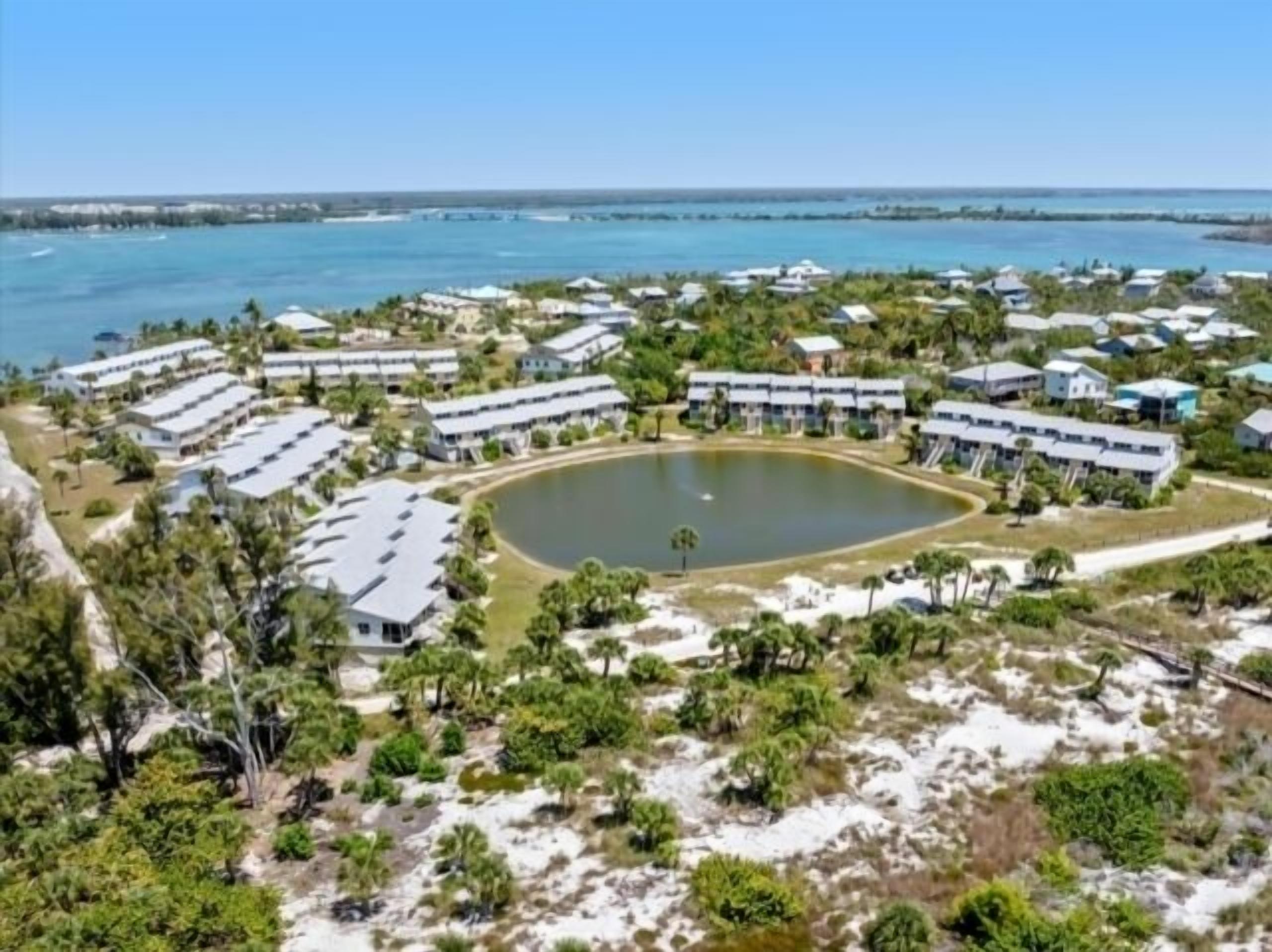 Ein Resort mit mehreren Gebäuden, einem zentralen Teich und umliegender Bepflanzung.