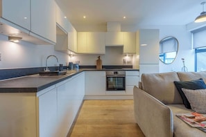 A modern kitchen with white cabinets, a built-in oven, and a wooden island.