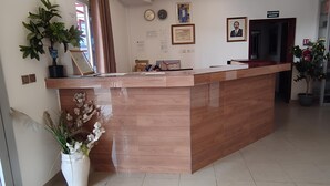 A reception desk with a wooden finish, a potted plant, and a framed certificate on the wall. - Hôtel Résidence Segmad de Kribi (Kribi)
