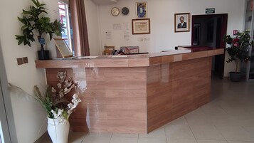 Una recepción con detalles de madera, una planta en maceta y un certificado enmarcado en la pared.