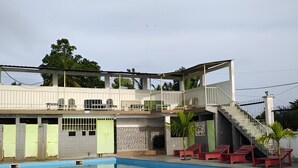 A swimming pool with a covered area, stairs, and a building with a balcony. - Hôtel Résidence Segmad de Kribi (Kribi)