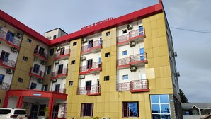 A multi-story hotel with balconies, air conditioning units, and a red and yellow facade. - Hôtel Résidence Segmad de Kribi (Kribi)