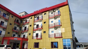 Un hotel de varios pisos con balcones, unidades de aire acondicionado y fachada roja y amarilla.
