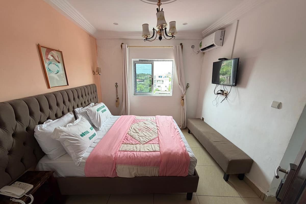 Ein Schlafzimmer mit Bett, einer Sitzbank, einem Fernseher und einem Fenster mit Blick.