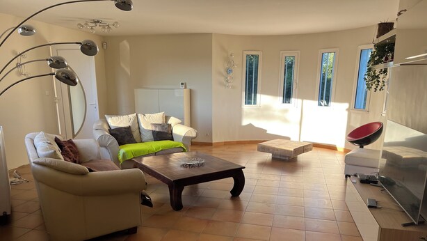 Ein Wohnzimmer mit einer Couch, einem Couchtisch, einem Fernseher und einem roten Sessel.