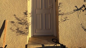 Eine weiße Tür mit kleinem Fenster darüber, eingebaut in eine strukturierte Wand.
