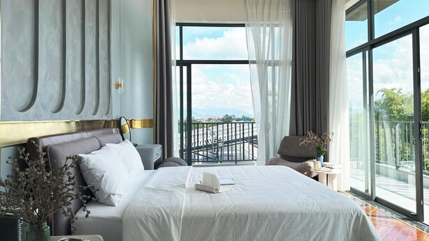 A hotel room with a large bed, a balcony with a view, and a modern design. - BB HOUSE: VILLA SANG TRỌNG TẠI BẢO LỘC (3 Bảo Lộc)