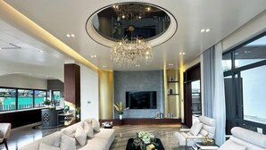 A modern living room with a large chandelier, a flat-screen TV, and a seating area with sofas and a coffee table. - BB HOUSE: VILLA SANG TRỌNG TẠI BẢO LỘC (3 Bảo Lộc)