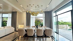 A modern dining room with a large table, chairs, and a chandelier. - BB HOUSE: VILLA SANG TRỌNG TẠI BẢO LỘC (3 Bảo Lộc)