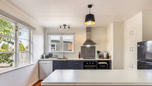 A modern kitchen with a central island, built-in appliances, and a large window. - Central Taupo Getaway by Aotearoa Escapes (Taupo)