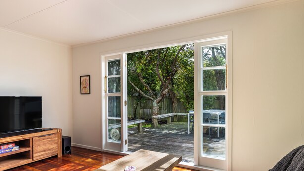 A living room with a TV, wooden entertainment unit, and a table. - Central Taupo Getaway by Aotearoa Escapes (Taupo)