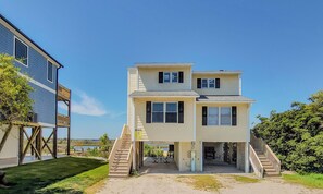 A two-story building with a covered patio area and a staircase leading to the entrance. - The Sandcastle: Renovated + Ready for You (Surf City)