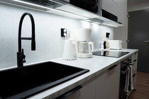 A modern kitchen with a black sink, white appliances, and a stainless steel range hood. - Snownest Premium City Centre Apartments 1 (Rovaniemi)