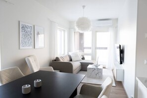 Uma sala de estar moderna com sofá, mesa de jantar e televisão.