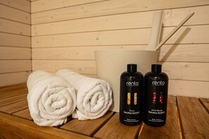 A sauna room with two rolled towels, a bucket, and two bottles of Rento sauna scents. - Snownest Premium City Centre Apartments 1 (Rovaniemi)