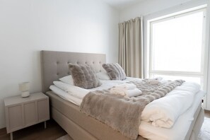A bedroom with a bed, nightstand, and window. - Snownest Premium City Centre Apartments 1 (Rovaniemi)