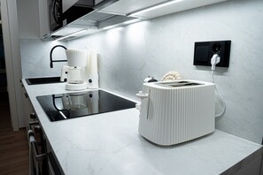 Eine moderne Küche mit weißer Arbeitsplatte, integriertem Backofen, Kaffeemaschine und Toaster.