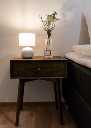 Een nachtkastje met een lamp en een vaas met bloemen.
