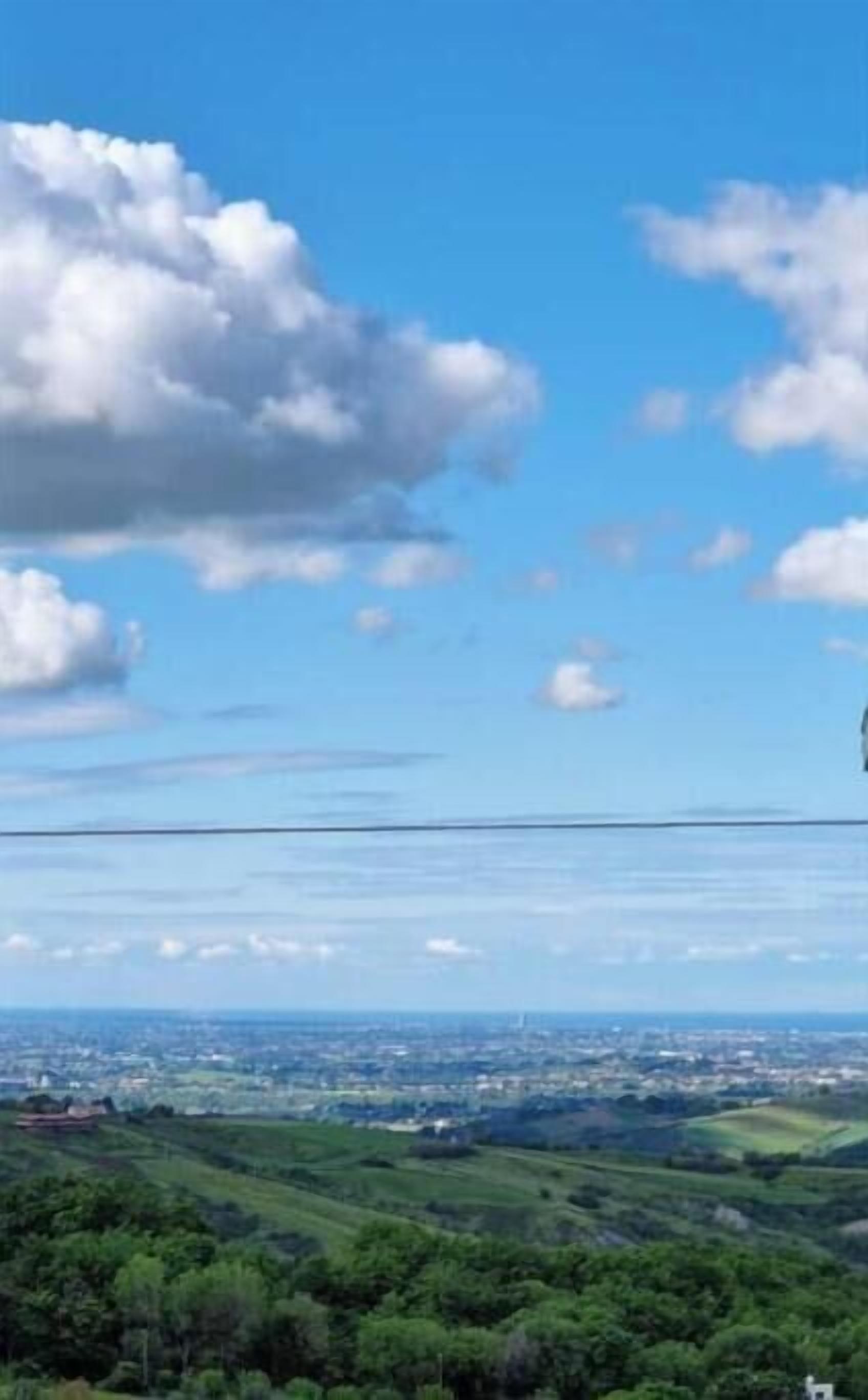 Une vue panoramique sur un paysage, avec un ciel dégagé et quelques nuages épars.