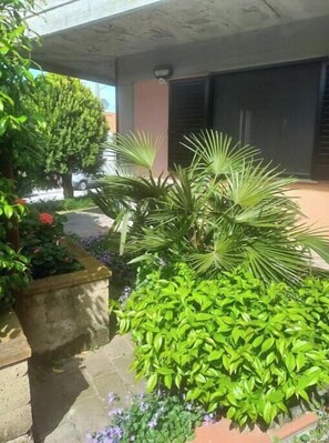 A building with a stone planter with green plants and a small tree. - Travel to San Marino - Relaxation and comfort in the world's oldest republic (Borgo Maggiore)
