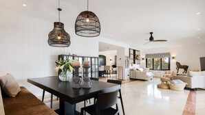 A modern living room with a dining area, featuring a sofa, a dining table, and a ceiling fan. - 3310 Villa Flores (Marbella)