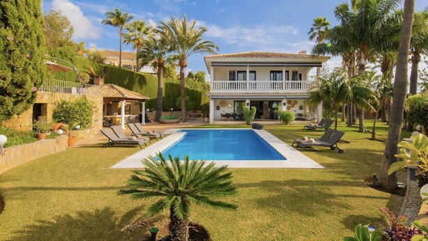 A two-story house with a swimming pool, surrounded by palm trees and a well-maintained lawn. - 3310 Villa Flores (Marbella)
