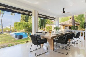 Ein moderner Essbereich mit Blick auf einen Pool, großen Fenstern und einem Deckenventilator.
