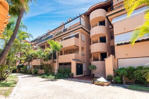 A multi-story hotel with balconies, a paved courtyard, and tropical landscaping. - 3316 Casa Jacaranda (Marbella)
